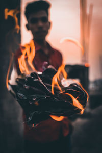 Close-up of man holding burning candle