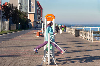 Woman on footpath in city against sky