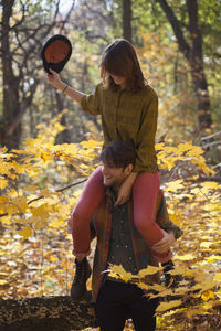 Young woman playfully sitting on her boyfriend's shoulders