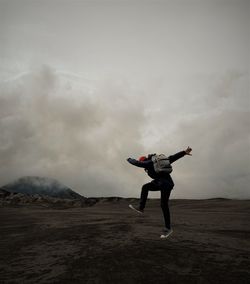Full length of man jumping on mountain against sky
