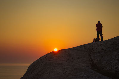 Man standing on cliff during sunset