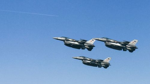 Low angle view of airplane flying against clear blue sky