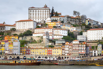 Buildings by river against sky in city