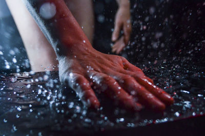 Close-up of hand touching rock during rainy season