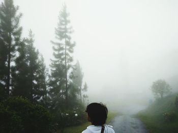 Rear view of man walking on landscape against sky