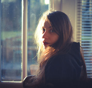 Side view of young woman standing by window