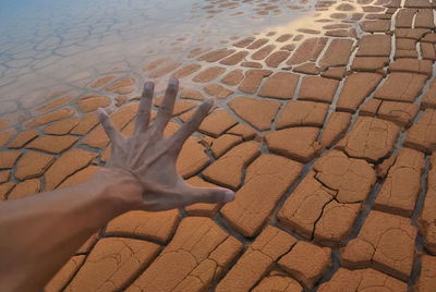 Cropped hand of man gesturing against rock