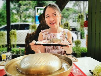 Portrait of a smiling girl holding food on table