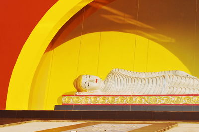 Statue against yellow and building