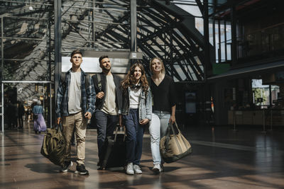 Family looking away while walking together with luggage at station