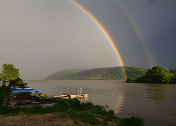 Scenic view of rainbow over river against sky