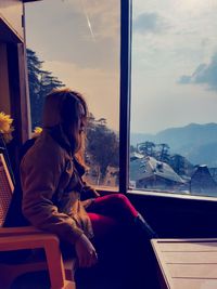 Side view of man looking through window