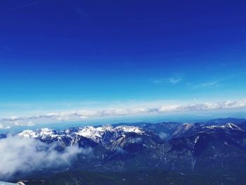 Scenic view of snowcapped mountains against blue sky