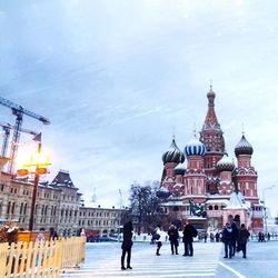 People on city by orthodox church against sky during winter