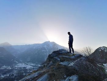 Man standing on snowcapped mountain against clear sky