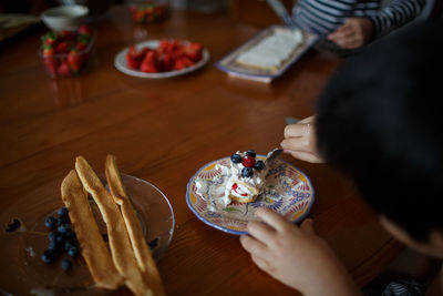 Cropped image of boy eating cake on table