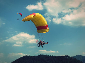 Low angle view of person paragliding against sky