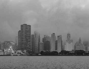 City at waterfront against cloudy sky