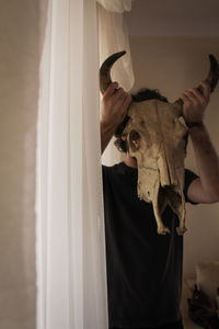 Close-up man holding animal skull in front of face
