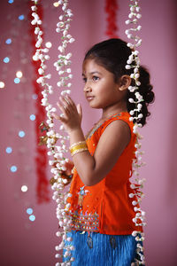 Side view of girl standing against curtain