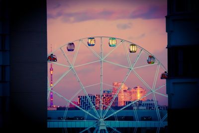 Illuminated ferris wheel against sky at sunset