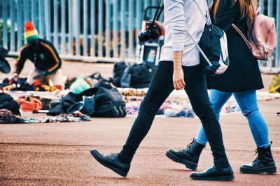 Low section of friends walking on footpath