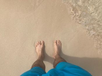 Low section of man standing on beach