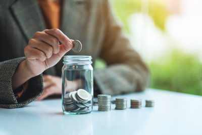 Midsection of woman holding jar on table