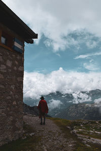 Rear view of man standing on building against sky