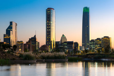 Modern buildings by river against sky in city