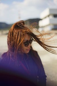 Close-up of woman with tousled hair wearing sunglasses at beach