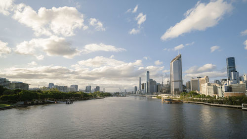 Buildings by river against sky