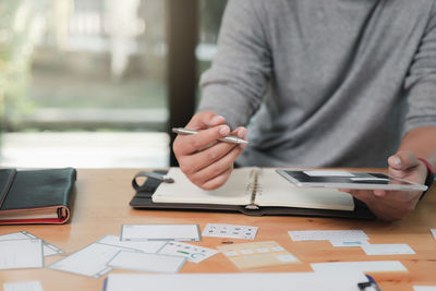 Midsection of man using mobile phone on table