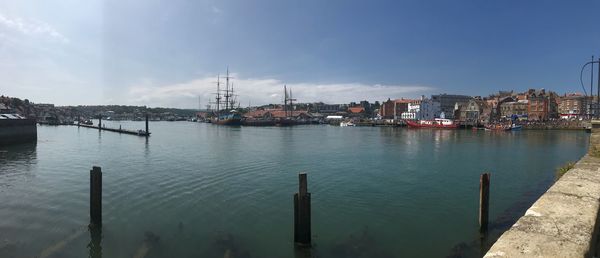 Sailboats moored in sea against sky in city