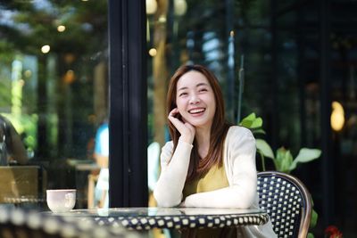 Portrait of young woman looking away while sitting in cafe