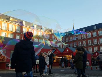 People in amusement park against sky in city