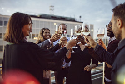 Business coworkers toasting wineglasses while celebrating in office party on terrace