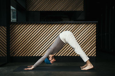 Side view of man skateboarding against wall