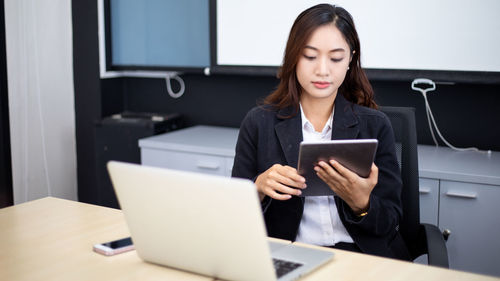 Portrait of young woman using laptop at table