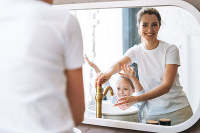 Young mother woman with little tween girl daughter in pajamas washing face and hands at home