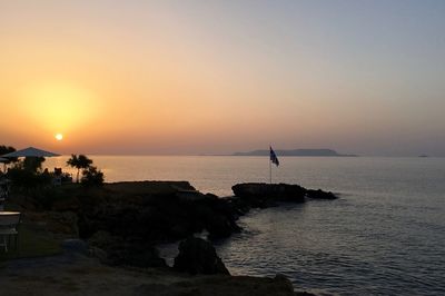 Silhouette man standing in sea against clear sky during sunset