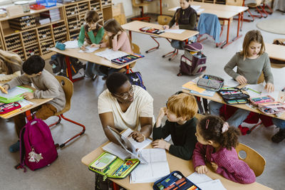 Teacher explaining male and female students sitting in classroom