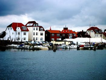 Houses by river against sky