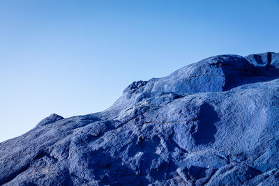 Low angle view of snowcapped mountain against clear blue sky