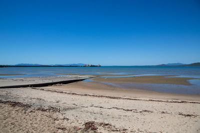 Scenic view of beach against clear blue sky