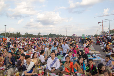 Group of people at music concert in city against sky