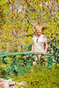 Senior woman standing on a beautiful forged bridge surrounded by greenery