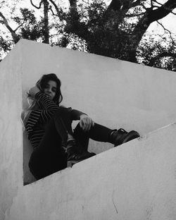 Portrait of woman sitting on retaining wall