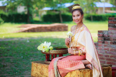 Portrait of smiling mid adult woman in traditional clothing sitting at park