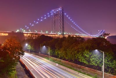 Light trails on suspension bridge against sky at night